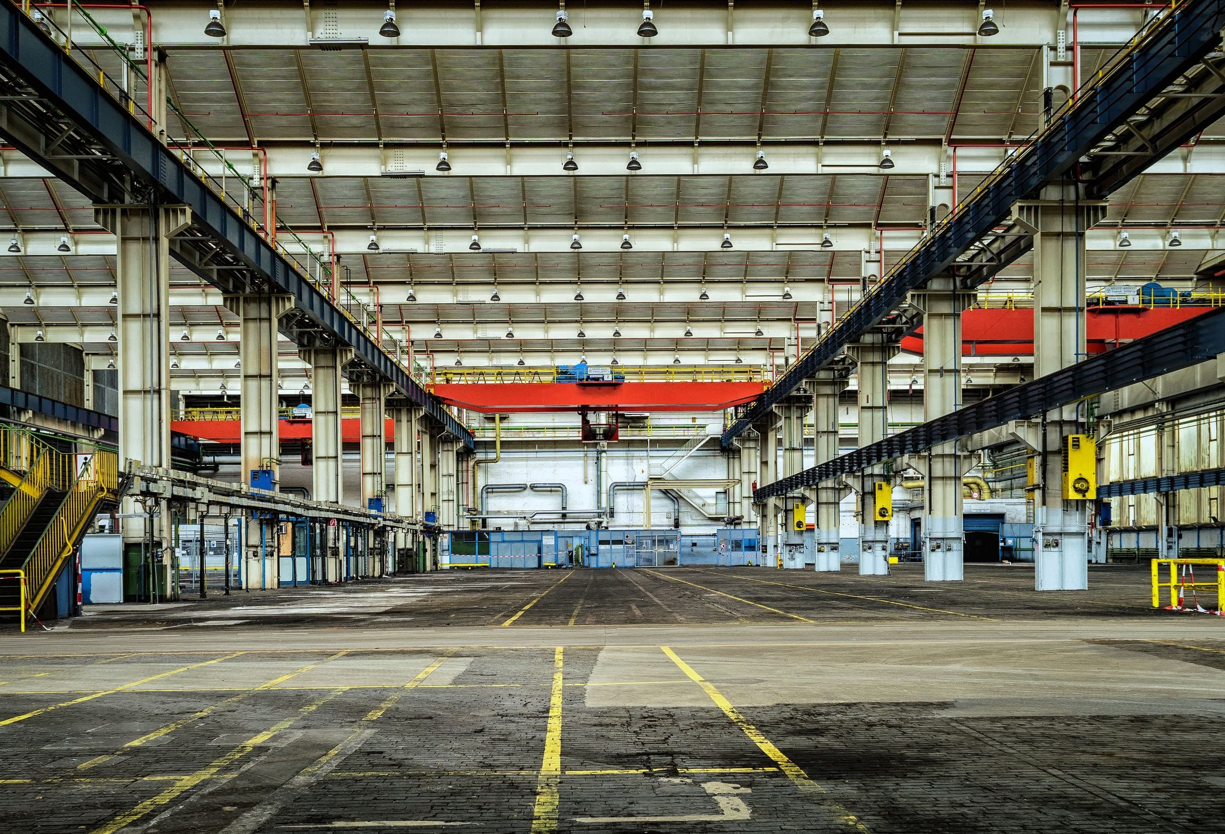 Industrial plant hall with overhead gantry cranes and production infrastructure